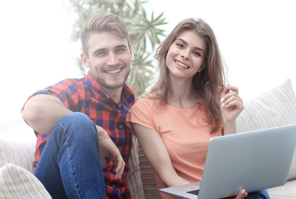 young couple of students with laptop sitting on the couch - Photo, Image