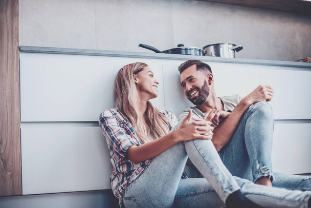 loving couple discussing something sitting on the kitchen floor - Photo, Image