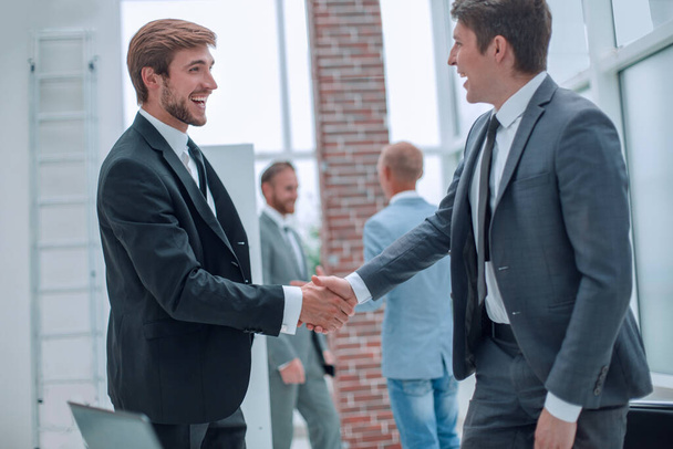 Счастливые бизнесмены пожимают друг другу руки в офисе
. - Фото, изображение