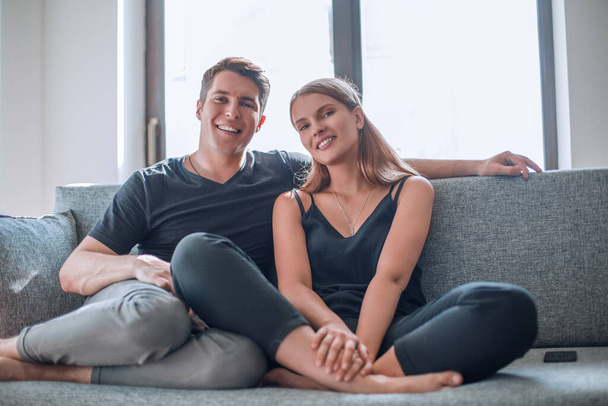 šťastný mladý pár sedí na gauči ve svém novém bytě . - Fotografie, Obrázek