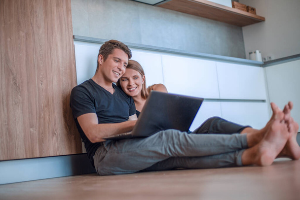 молода пара використовує ноутбук, що сидить на підлозі нової квартири
 - Фото, зображення