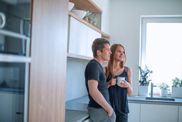 happy young couple standing in the kitchen in their house. - Фото, зображення