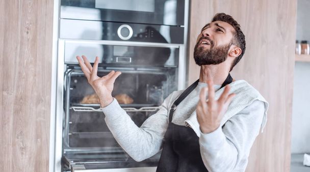 "homem surpreso de pé perto do forno com croissants queimados." - Foto, Imagem