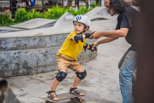 "Athletic boy learns to skateboard with a trainer in a skate park. Children education, sports" - Φωτογραφία, εικόνα