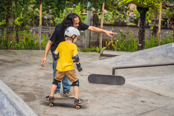 "Der sportliche Junge lernt in einem Skatepark mit einem Trainer das Skateboardfahren. Kindererziehung, Sport" - Foto, Bild