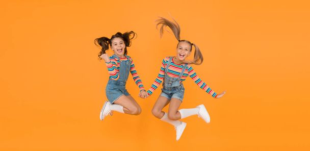 party fun time. little girls jump yellow wall. sense of freedom. finally summer vacation. free and energetic beauty. happy childhood. real friendship. best friends forever. small sisters have fun. - Фото, зображення