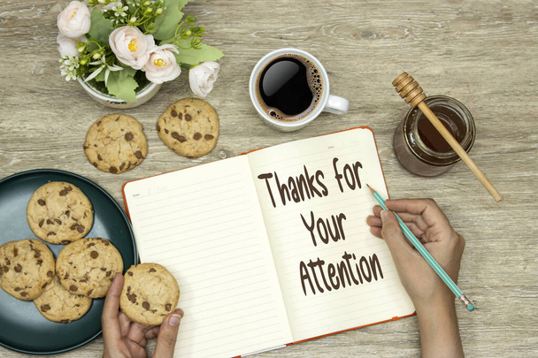 hands writing Thank you for your attention on notebook and eating homemade cookies  - 写真・画像