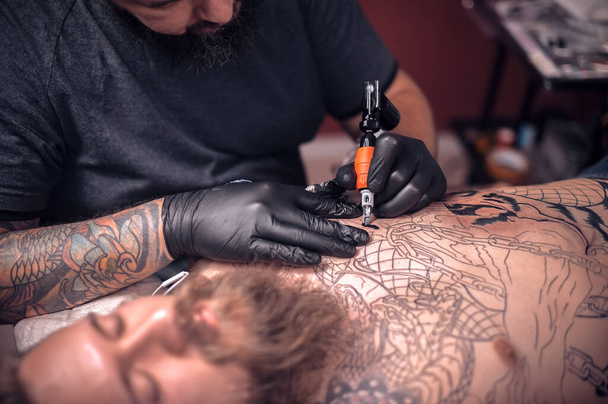 Tattooer working on professional tattoo machine device in tattoo studio - Photo, Image