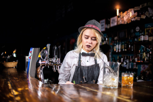Selbstbewusste Barkeeperin gießt an Bar frisches alkoholisches Getränk in die Gläser - Foto, Bild