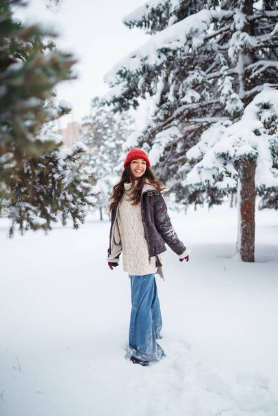 Beautiful woman standing among snowy trees and enjoying first snow. Holidays, rest, travel concept. - Foto, Imagen