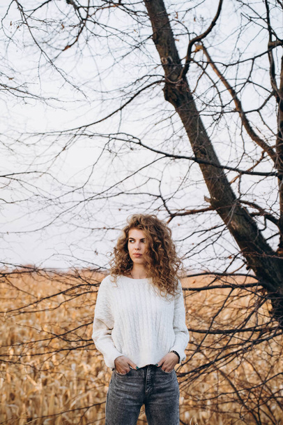 秋の自然と自分の車を背景に白いセーターを着た少女。高品質の写真 - 写真・画像