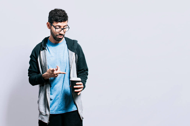 "Osoba z kawą na odosobnionym tle, facet wskazujący jednorazową filiżankę kawy na odizolowanym tle, koncepcja mężczyzny patrzącego na jednorazową filiżankę kawy" - Zdjęcie, obraz