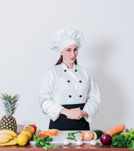 "Портрет шеф-повара женского пола в окружении свежих овощей, портрет шеф-повара женского пола со свежими овощами на столе, женщина-диетолог со столом из овощей" - Фото, изображение