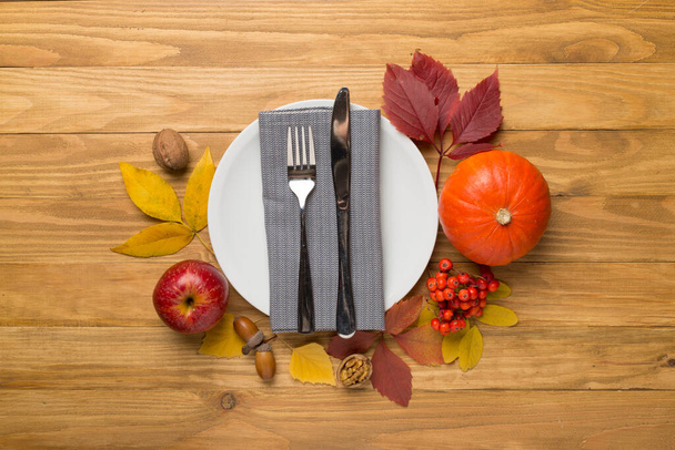 Bord met bestek, servet en herfstdecor op houten ondergrond, bovenaanzicht. Thanksgiving tafel dekken. - Foto, afbeelding