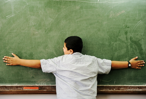 Schoolchild hugging board in classroom - Valokuva, kuva