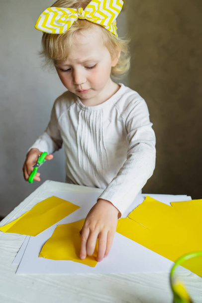 Маленька дівчинка ріже папір за допомогою ножиць. Вишукані мотори для дітей. Навчання ножиць навичкам дошкільнят
. - Фото, зображення