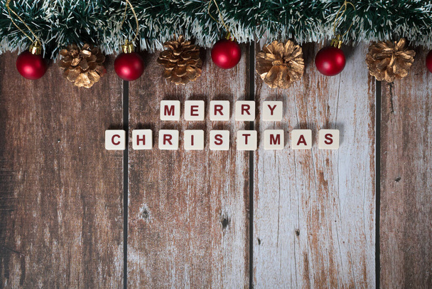 Vrolijk kerstfeest geschreven met letters van een spel en kerstversieringen op een houten achtergrond - Foto, afbeelding
