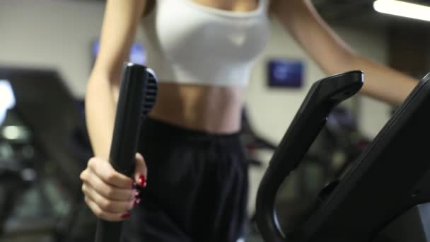 Egy nő, aki elliptikus járógéppel edz a tornateremben. Fitness lány képzés gyalogos gép. - Felvétel, videó