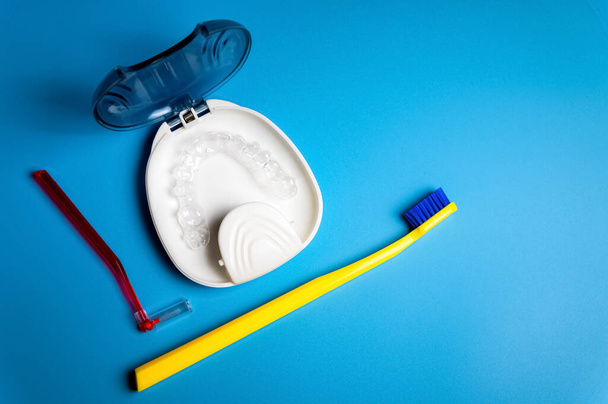 "Unsichtbare Zahnspangen für Zähne, transparente Zahnausrichtungen, Kunststoffspangen, Halterungen zum Richten der Zähne, Zahnbürste und Interdentalbürste auf blauem Hintergrund, Ansicht von oben" - Foto, Bild