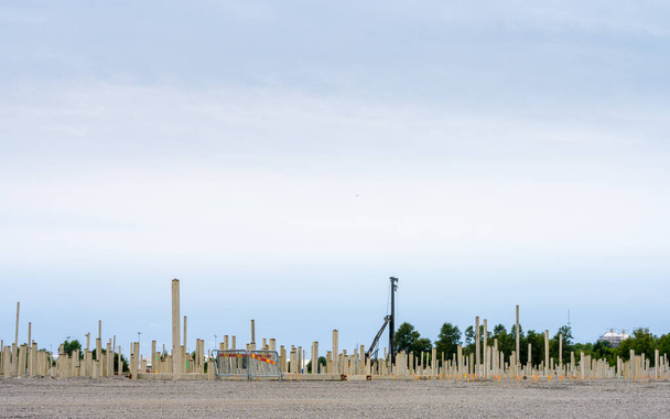 Γκέτεμποργκ, Σουηδία - 24 Ιουλίου 2022: Πολλοί τσιμεντένιοι σωροί οδηγούνται στο έδαφος για να δημιουργήσουν θεμέλια για μια μεγάλη αποθήκη. - Φωτογραφία, εικόνα