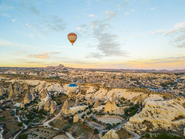 Breathtaking drone view of hot air balloons flying over the Red Valley in Cappadocia in Turkey at dawn. Fairy chimneys or hoodoos during the sunrise. High quality photo - Photo, image