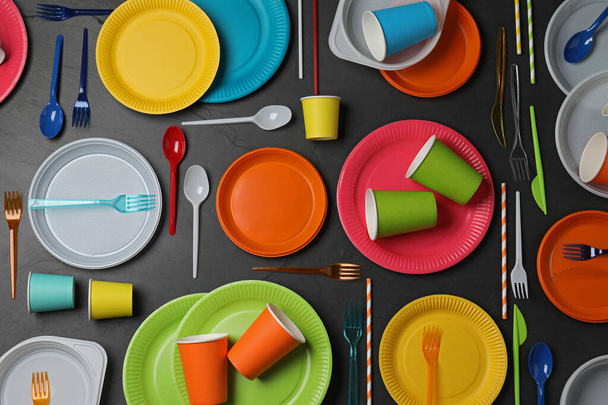 Flat lay composition with different disposable tableware on black background - Foto, Imagen