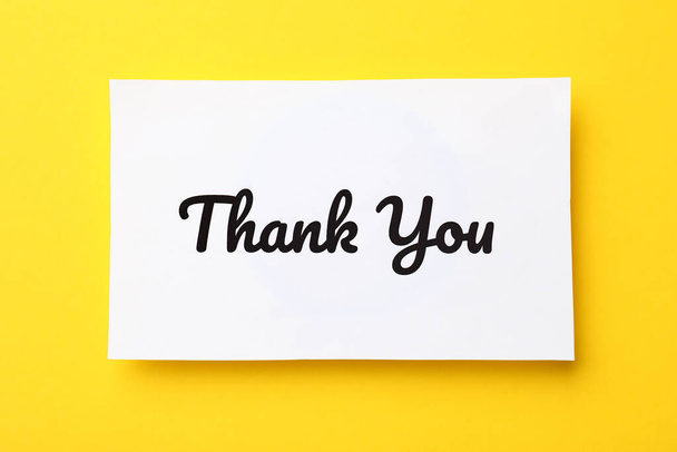 White paper note with phrase Thank You on yellow background, top view - Foto, immagini