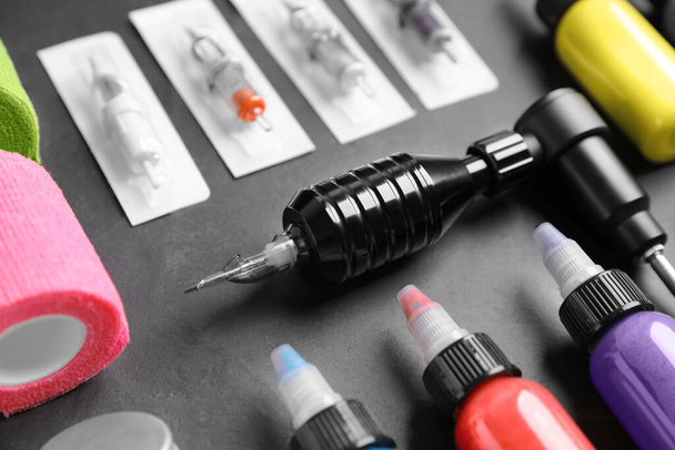 Tattoo machine and inks on black table, closeup - Valokuva, kuva