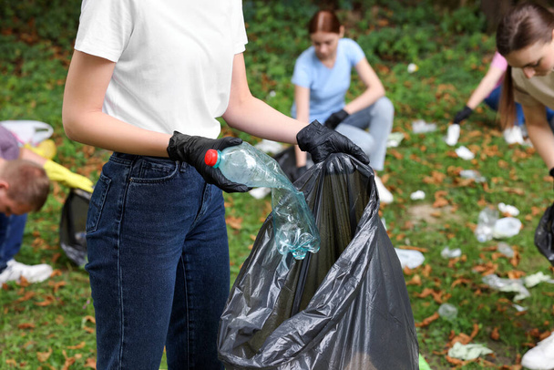 Woman with plastic bag collecting garbage in park, closeup - Zdjęcie, obraz