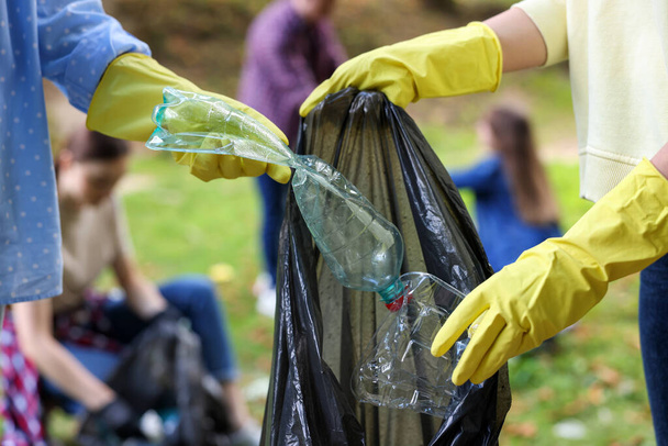 Women with plastic bag collecting garbage in park, closeup - Foto, Bild