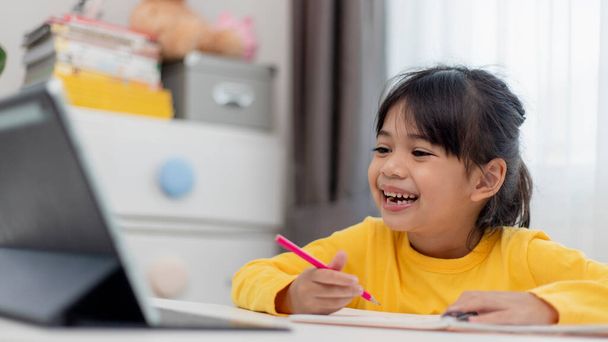 アジアの女の子は、オンラインでクラスを取り、家庭学校の隔離のために幸せ｜Coranavirusパンデミックの概念 - 写真・画像