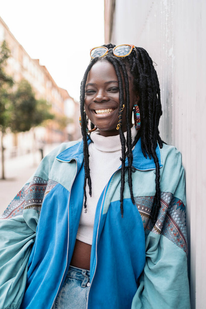 Happy and young african woman with cool braids smiling and looking at camera. She is in the street. - Fotografie, Obrázek