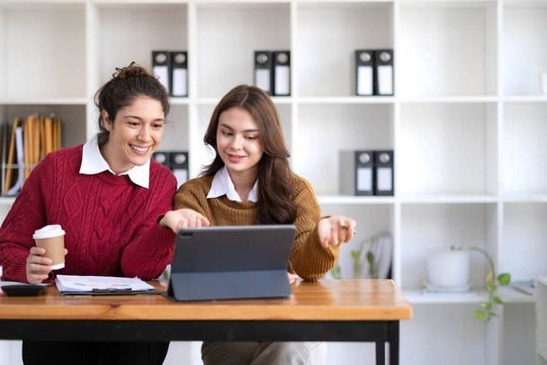 Two young Asian business woman talk, consult, discuss working with new startup project idea presentation analyze plan marketing and investment in the office... - Photo, image