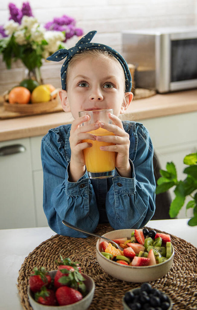 Zdrowe jedzenie w domu. słodkie mała dziewczyna je owoce sałatka  - Zdjęcie, obraz