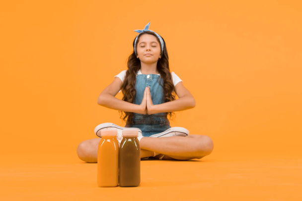 Stay positive and optimistic. Healthy way of life. Yoga training. KId girl sit meditate. Meditating practice. Good vibes. Peaceful meditating. Vegetarian smoothie drink. Learn meditating techniques. - 写真・画像