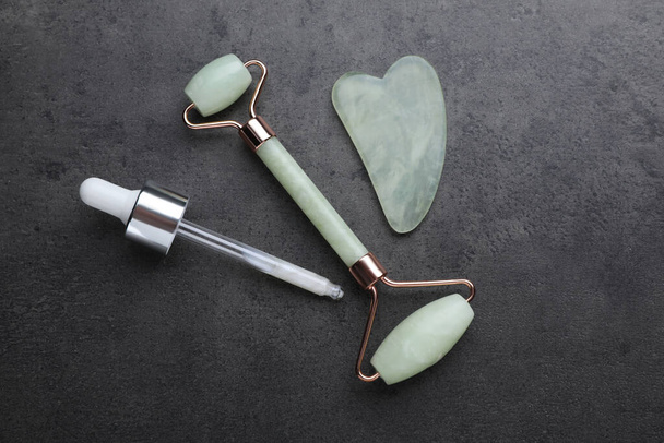 Quartz gua sha tool, face rollers and dropper with cosmetic product on grey background, flat lay - Фото, зображення