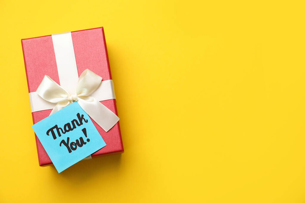Gift box and light blue paper note with phrase Thank You on yellow background, top view. Space for text - Photo, image