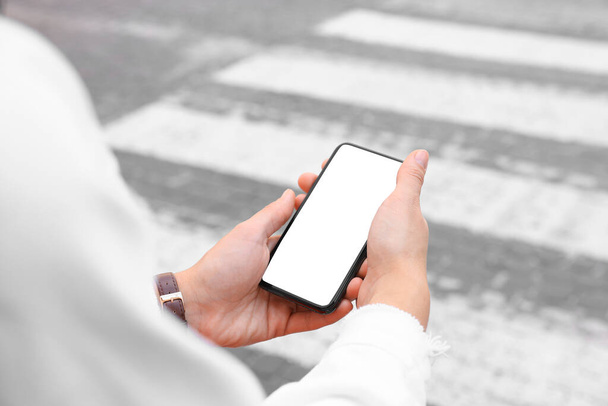 Woman with smartphone on pedestrian crossing, closeup - Photo, image