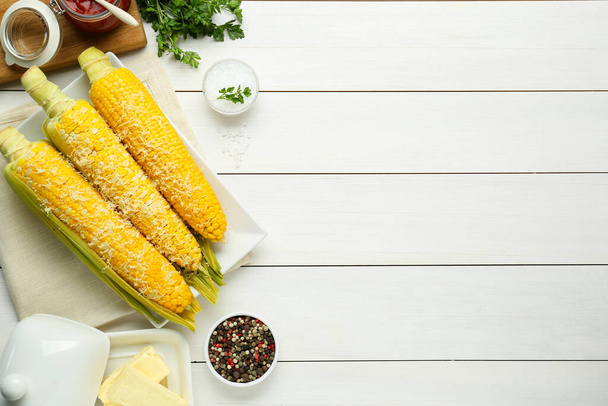 Plate with tasty cooked corn cobs on white wooden table, flat lay. Space for text - Photo, image