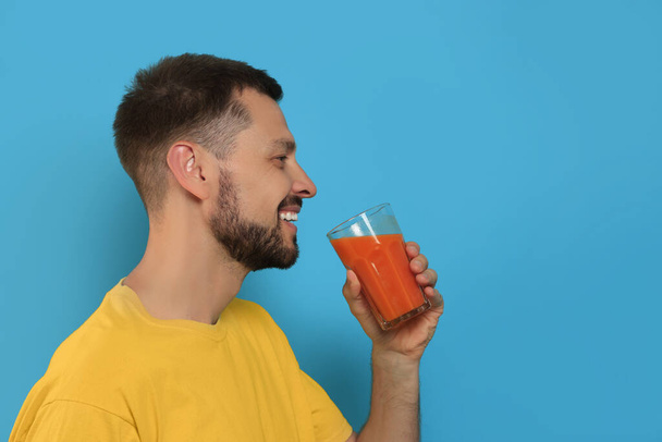 Man drinking delicious juice on light blue background, space for text - Foto, imagen