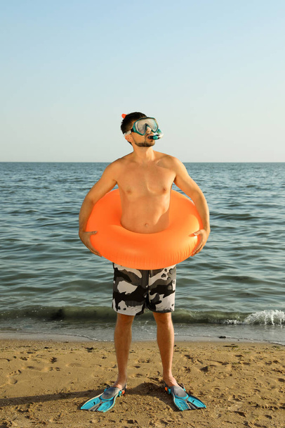 Hombre con aletas, anillo inflable y gafas en la playa de mar - Foto, imagen