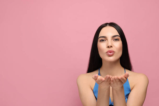 Beautiful young woman blowing kiss on pink background. Space for text - Фото, зображення