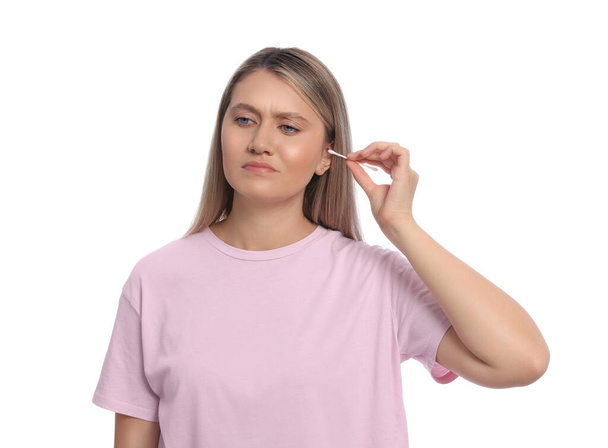 Young woman cleaning ear with cotton swab on white background - Fotó, kép