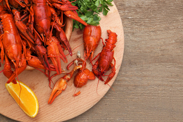 Delicious red boiled crayfish and orange on wooden table, top view. Space for text - Fotografie, Obrázek