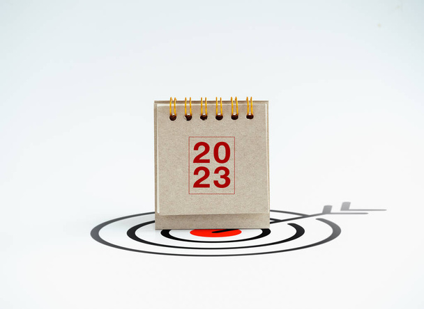 2023 yılınız kutlu olsun. 2023 yıllık masa takvimi kapağı beyaz arka planda izole edilmiş büyük hedef simgesi üzerinde duruyor. İş hedefleri ve başarı, eylem planı kavramları. - Fotoğraf, Görsel