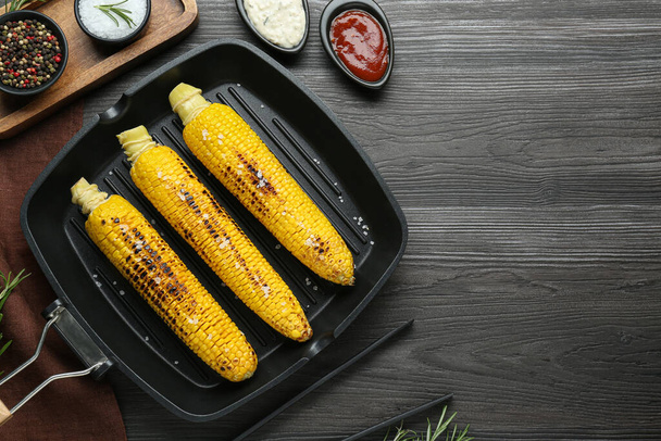 Flat lay composition with tasty grilled corn on dark grey wooden table. Space for text - Zdjęcie, obraz