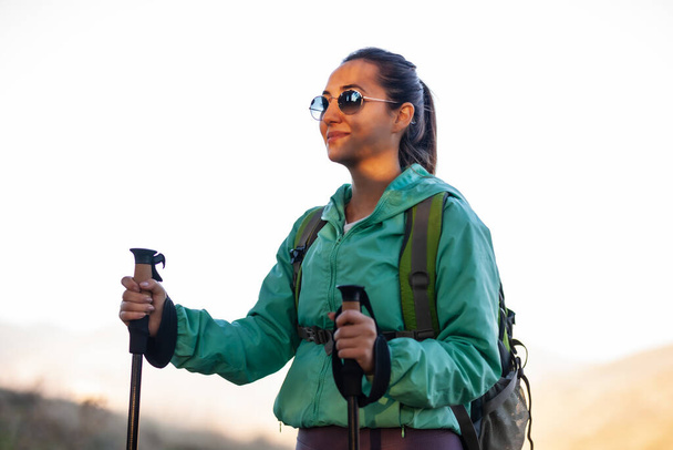 Backpacker hiker girl with hiking poles during sunset in the mountains. - Foto, immagini