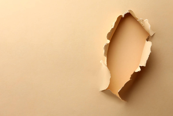 Hole in light beige paper on color background, space for text - 写真・画像
