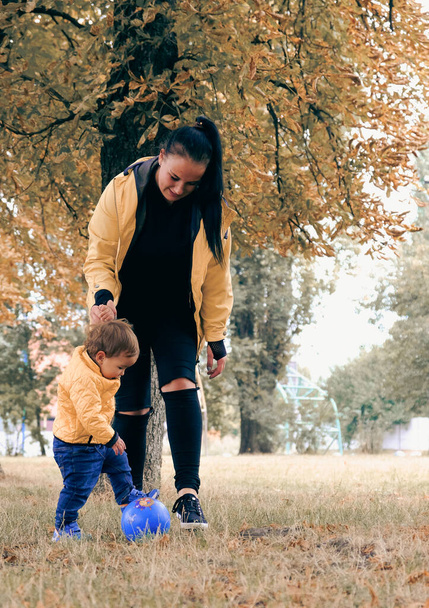 Das Kindermädchen spielt mit dem Kind auf dem Spielplatz. Mama mit Baby geht bei Herbstwetter im Park spazieren. Rutschen für Kinder. Kinderlachen, Spaziergang an der frischen Luft - Foto, Bild
