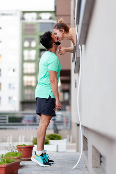 Couple in love. Boy standing outdoors kissing a girl from within a window. - Foto, Bild